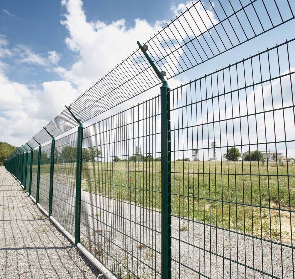Close-up of a black metal fence against a vibrant red background, creating geometric patterns.